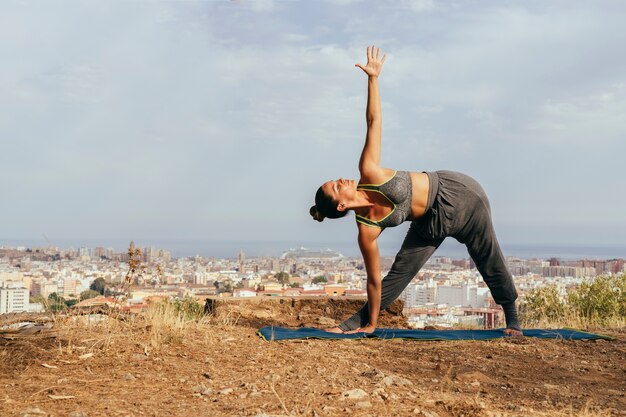 Mujer haciendo yoga con la ciudad al fondo