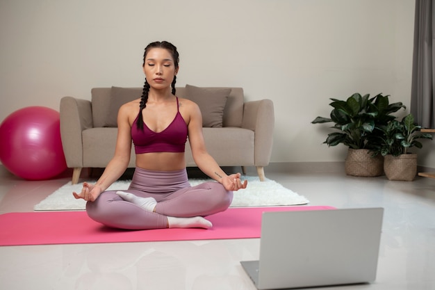 Mujer haciendo yoga después de instructor de fitness en línea