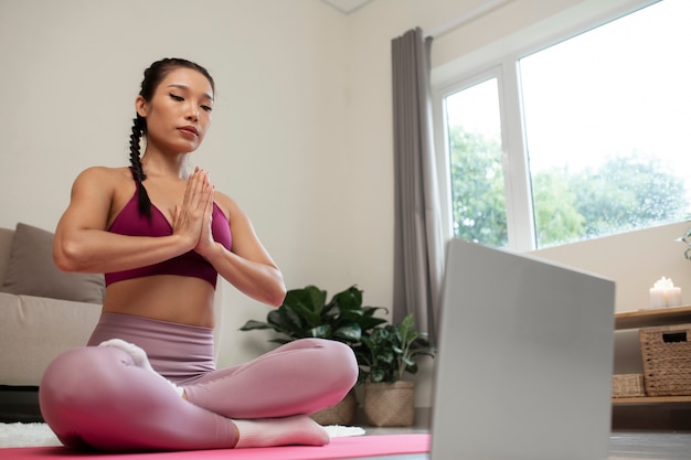 Foto gratuita mujer haciendo yoga después de instructor de fitness en línea