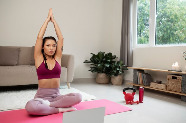 Mujer haciendo yoga después de instructor de fitness en línea