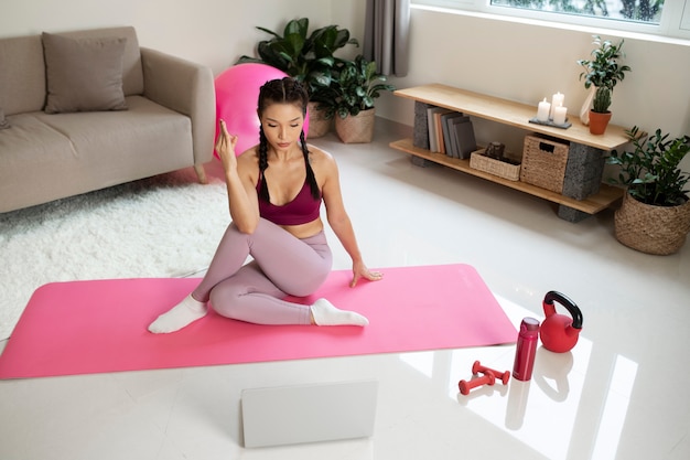 Mujer haciendo yoga después de instructor de fitness en línea