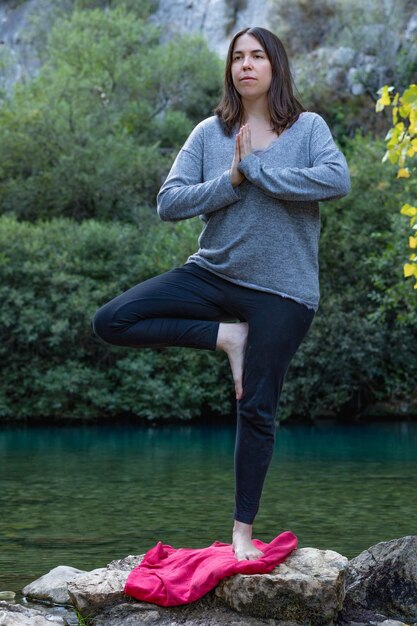 mujer haciendo yoga y meditación en un río