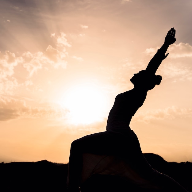 Mujer haciendo yoga con la puesta de sol