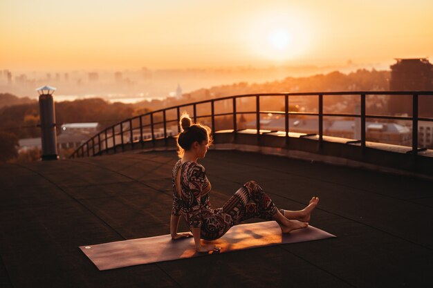 Mujer haciendo yoga en el techo de un rascacielos en la gran ciudad.