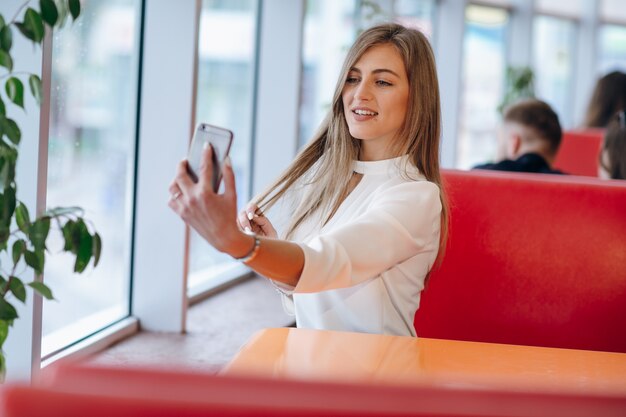 Mujer haciéndose una foto con su móvil a sí misma mientras sonrie
