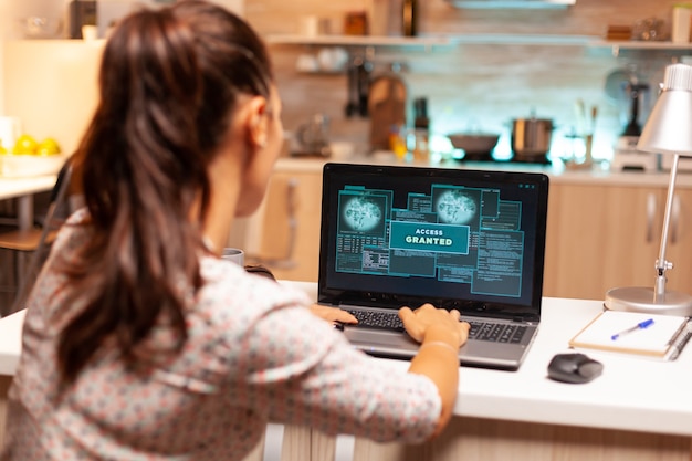 Mujer hacker lanzando un ciberataque en el firewall del banco desde casa durante la noche. Programador que escribe un malware peligroso para ataques cibernéticos utilizando una computadora portátil de rendimiento durante la medianoche.