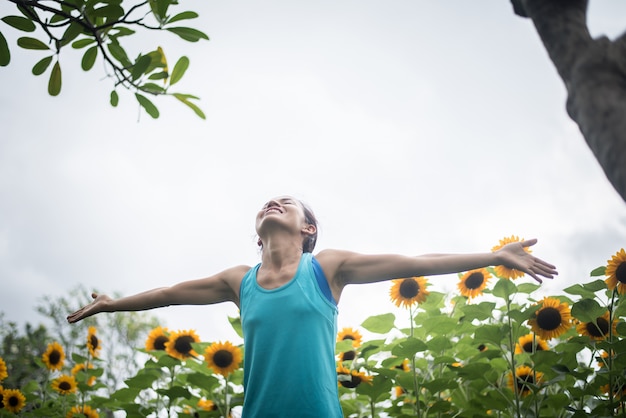 Foto gratuita mujer hermosa con el aumento de las manos en un campo de girasoles en el verano.