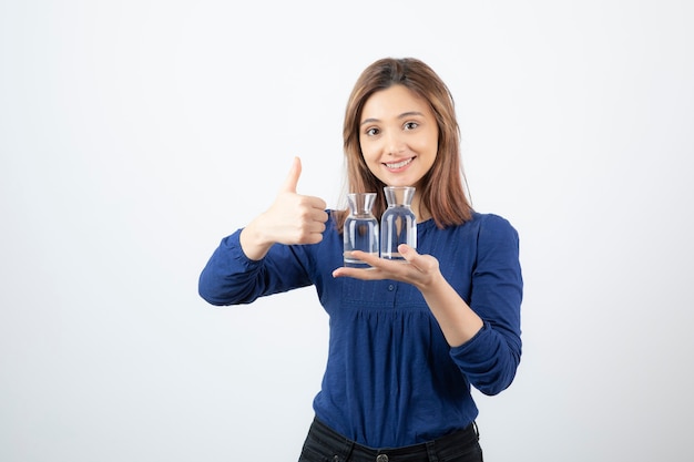 Mujer hermosa en blusa azul sosteniendo un vaso de agua y dando pulgares.