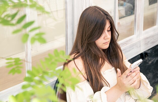 Una mujer hermosa con cabello largo usa un teléfono inteligente en un día de verano