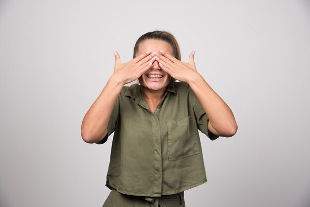 Mujer hermosa en camisa verde que cubre sus ojos.