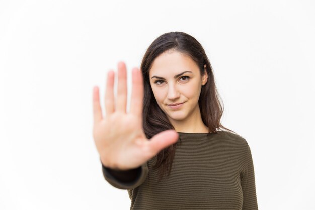 Mujer hermosa confiada seria que hace gesto de la parada de la mano