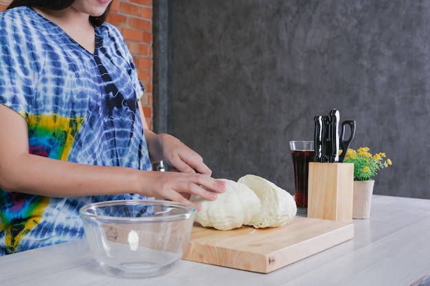 Foto gratuita una mujer hermosa está cortando verduras en la cocina en casa.