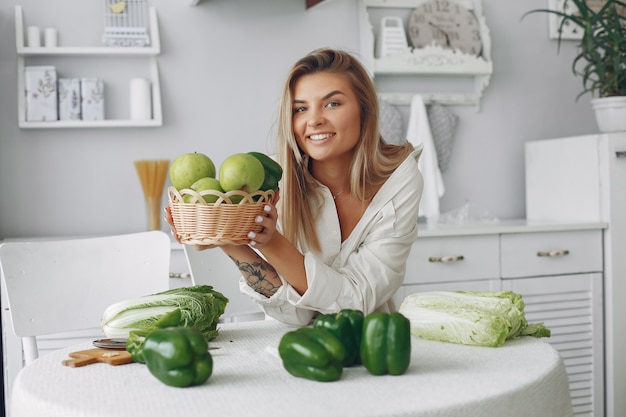 Mujer hermosa y deportiva en una cocina con verduras