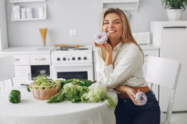 Mujer hermosa y deportiva en una cocina con verduras