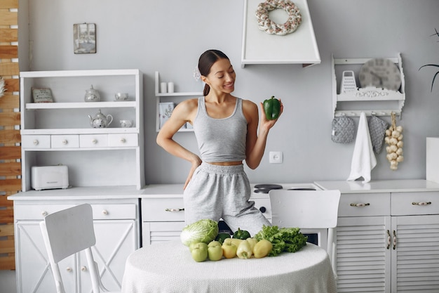 Mujer hermosa y deportiva en una cocina con verduras