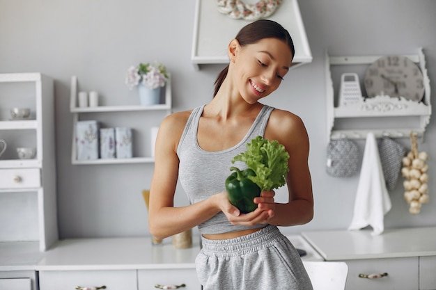 Mujer hermosa y deportiva en una cocina con verduras