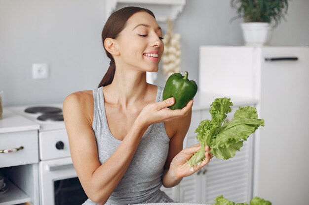 Mujer hermosa y deportiva en una cocina con verduras