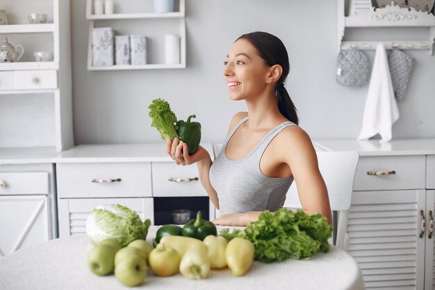 Mujer hermosa y deportiva en una cocina con verduras