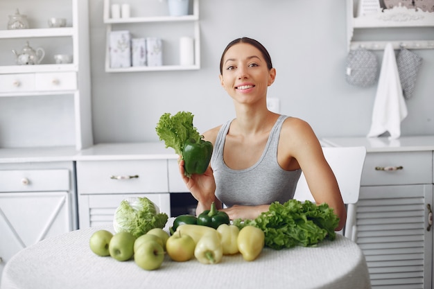 Mujer hermosa y deportiva en una cocina con verduras