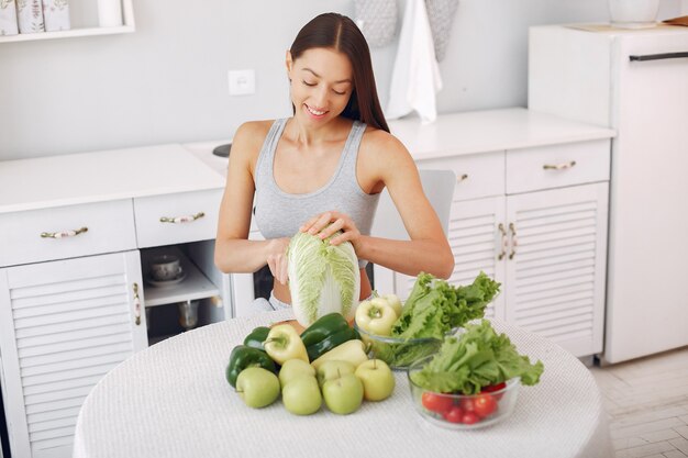 Mujer hermosa y deportiva en una cocina con verduras