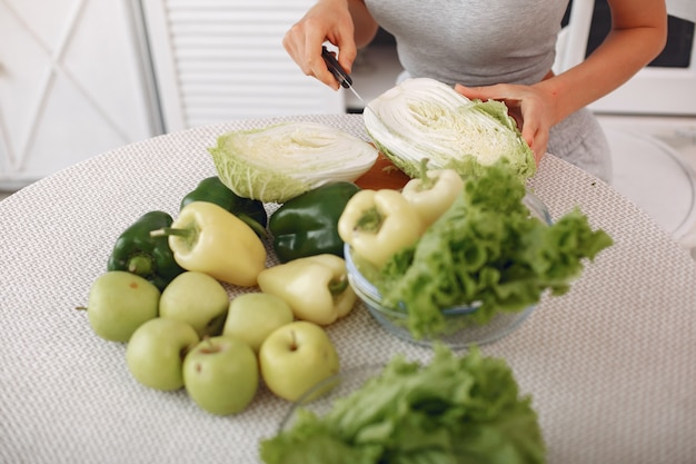 Mujer hermosa y deportiva en una cocina con verduras