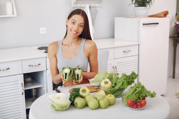 Mujer hermosa y deportiva en una cocina con verduras