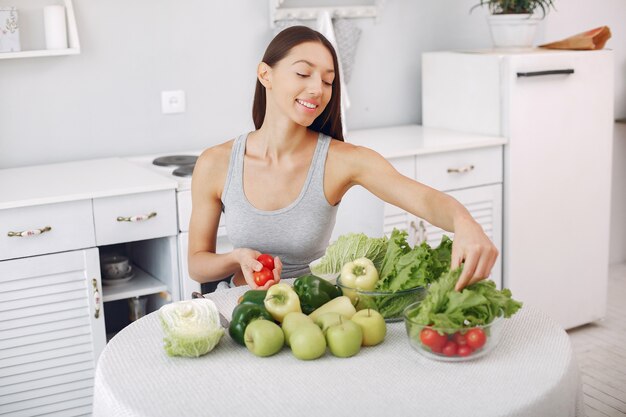 Mujer hermosa y deportiva en una cocina con verduras