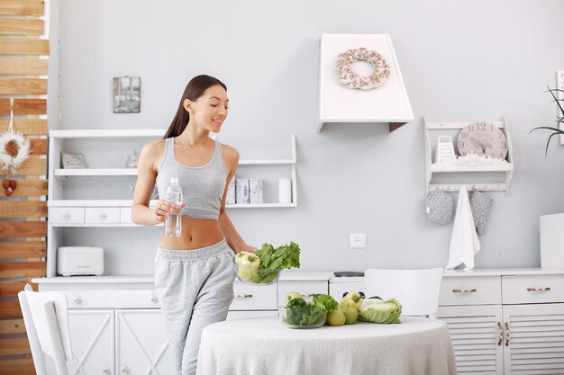 Mujer hermosa y deportiva en una cocina con verduras