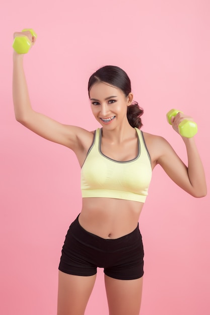 Mujer hermosa deportiva que ejercita con pesa de gimnasia