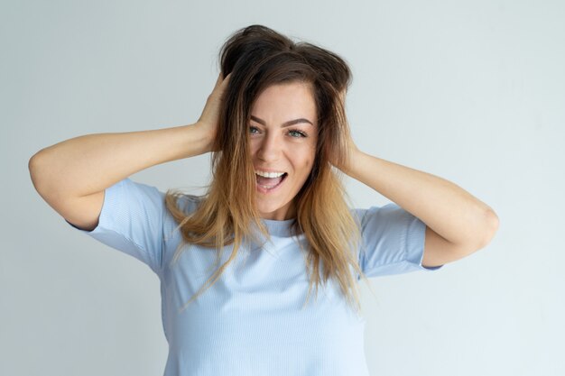 Mujer hermosa descuidada que toca el pelo y que mira la cámara. Señora emocionada.