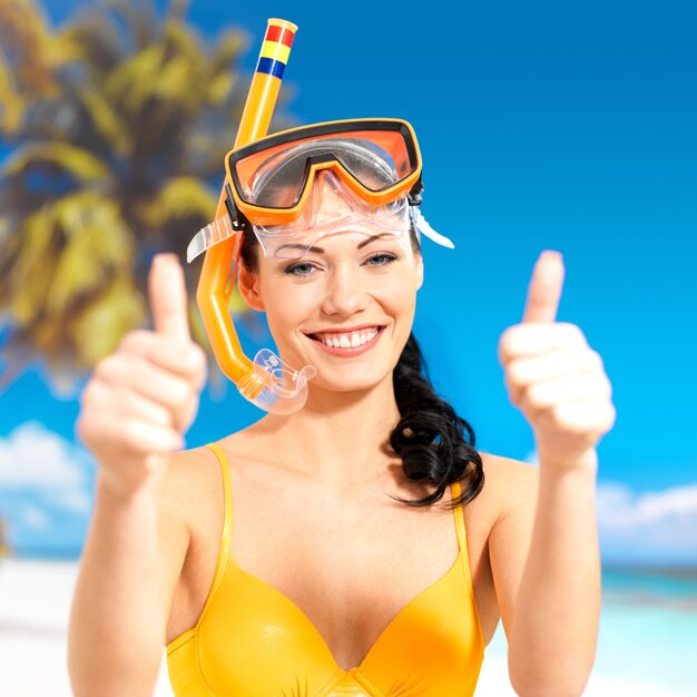 Mujer hermosa feliz en la playa con el pulgar hacia arriba signo.