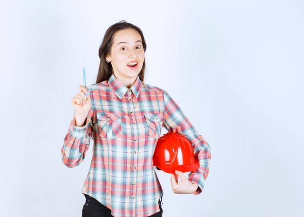 Mujer hermosa joven arquitecto con casco de seguridad con lápiz.