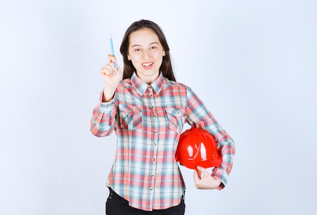 Mujer hermosa joven arquitecto con casco de seguridad con lápiz.