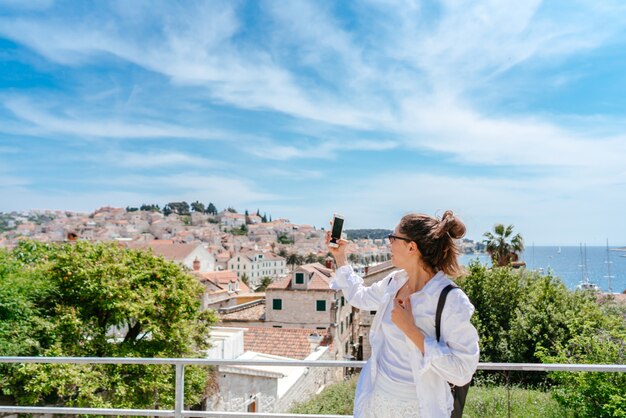 Mujer hermosa joven en un balcón con vistas a un pequeño pueblo en Croacia