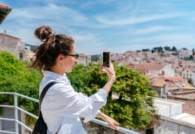 Mujer hermosa joven en un balcón con vistas a un pequeño pueblo en Croacia