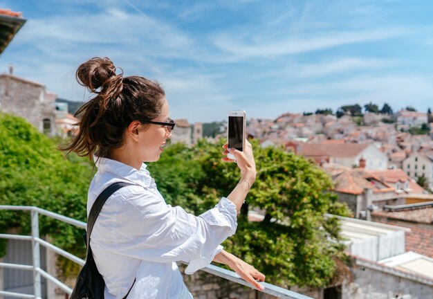 Mujer hermosa joven en un balcón con vistas a un pequeño pueblo en Croacia