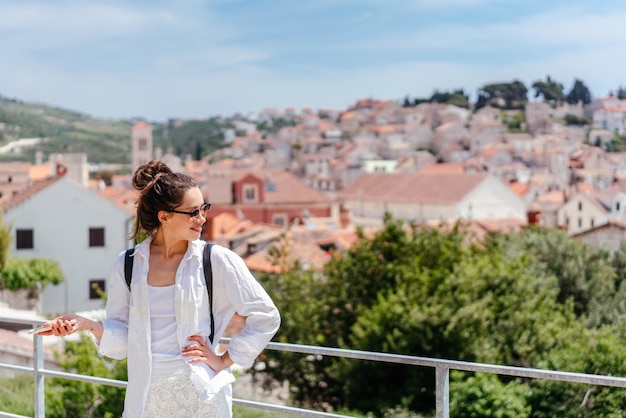 Mujer hermosa joven en un balcón con vistas a un pequeño pueblo en Croacia