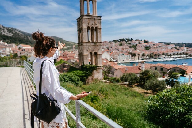 Mujer hermosa joven en un balcón con vistas a un pequeño pueblo en Croacia