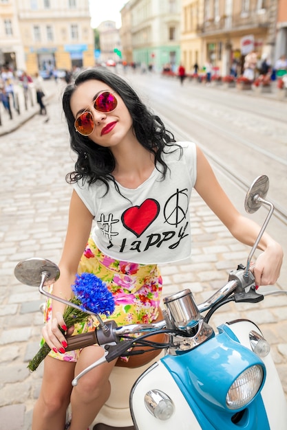 Mujer hermosa joven cabalgando en la calle de la ciudad de motos