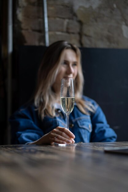 Mujer hermosa joven en un café, una mujer bebiendo champán en un café y hablando.