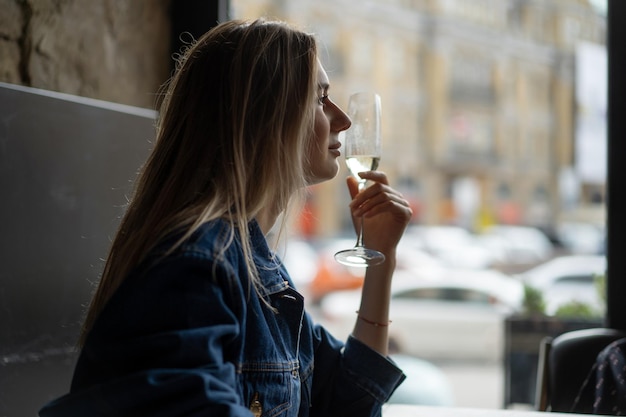 Mujer hermosa joven en un café, una mujer bebiendo champán en un café y hablando.