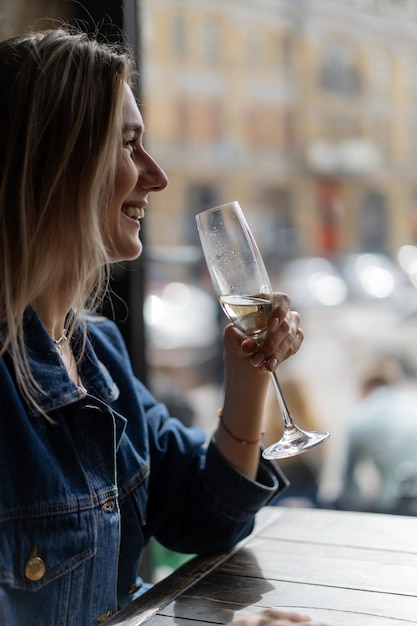 Mujer hermosa joven en un café, una mujer bebiendo champán en un café y hablando.