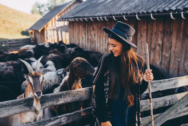 Una mujer hermosa joven cerca de un corral con cabras