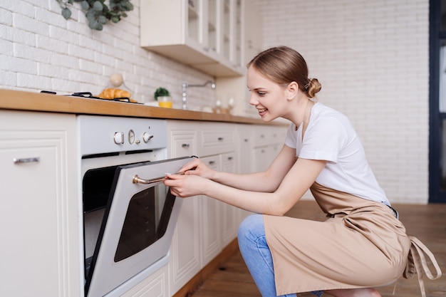 Foto gratuita mujer hermosa joven en la cocina en un delantal para hornear