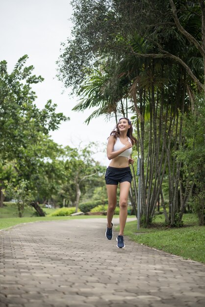 Mujer hermosa joven del deporte que corre en el parque. Concepto de salud y deporte.