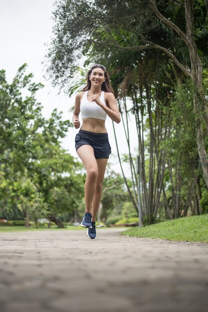 Mujer hermosa joven del deporte que corre en el parque. Concepto de salud y deporte.