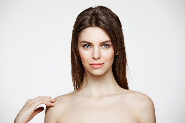 Mujer hermosa joven desnuda con maquillaje natural sonriendo. Cosmetología y spa. Tratamiento facial.
