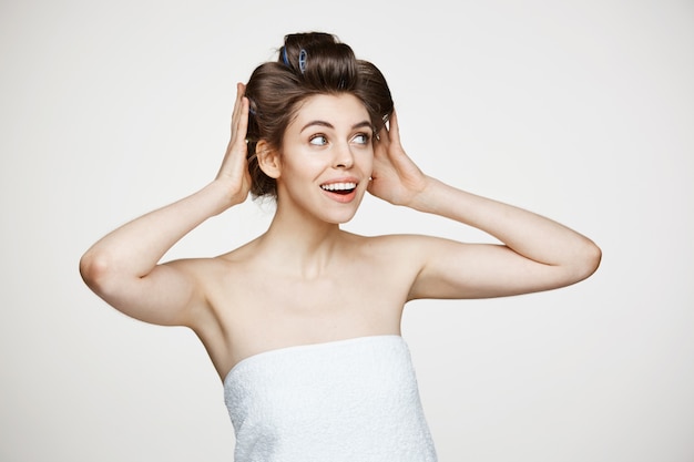 Mujer hermosa joven divertida en rizadores de pelo y toalla posando. Cosmetología de belleza y spa.