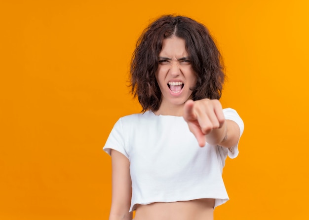 Mujer hermosa joven enojada apuntando en la pared naranja aislada con espacio de copia