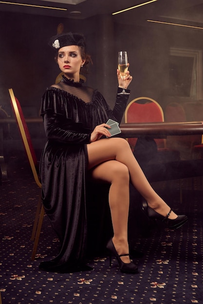 Mujer hermosa joven está posando contra una mesa de póquer en un casino de lujo.